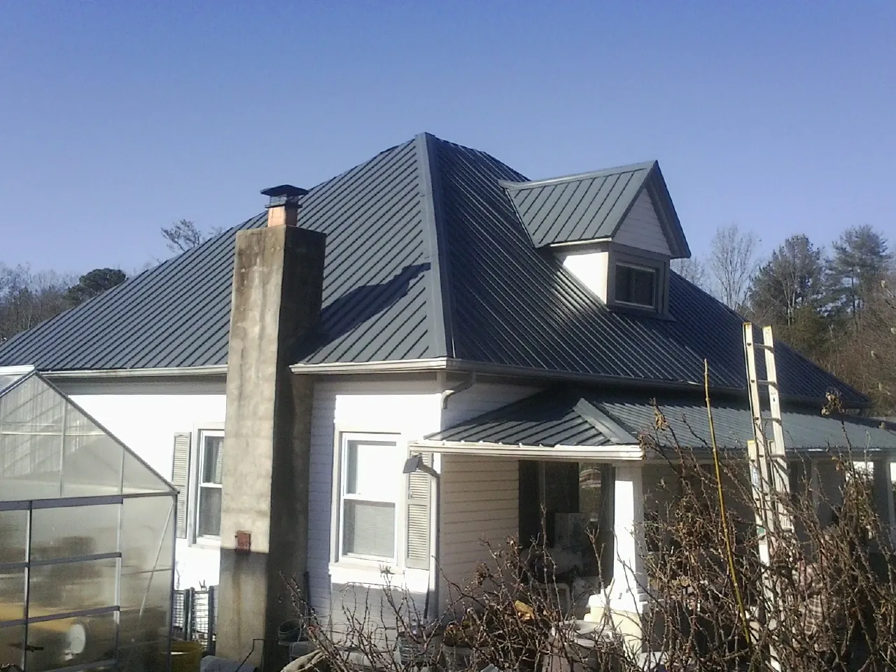 Dark blue standing seam metal roof on a white farmhouse with dormer — Slate & Tile Roof Repair by Roofing Brothers in Nucla