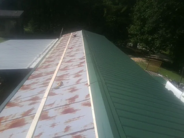 Old rusted panels beside newly installed green metal roofing — Wind Damage Roof Repair by Roofing Brothers in Nucla