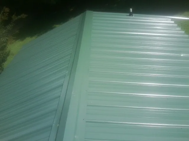 New green metal panels meeting at the ridge of a roof — Flat Roof Repair work by our crew in Nucla