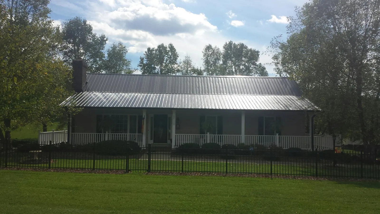 Gray metal roof on a brick ranch with a full width front porch — Gutter Guard Installation work by our crew in Nucla