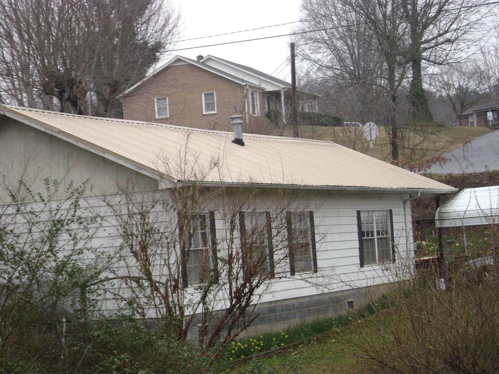 Tan metal roof on a white sided house set into a hillside — Commercial Roofing by Roofing Brothers in Nucla