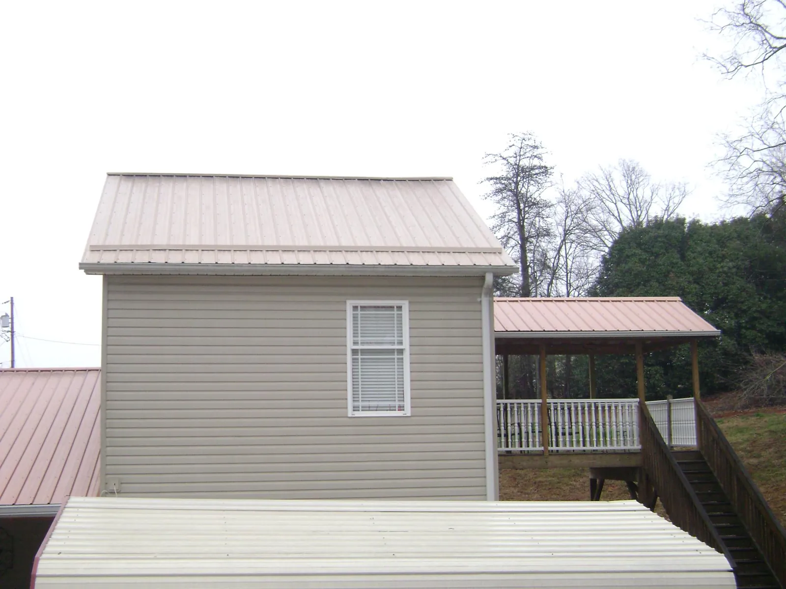 Tan metal roofs on a two story addition and attached porch, from a Roof Replacement job in Nucla