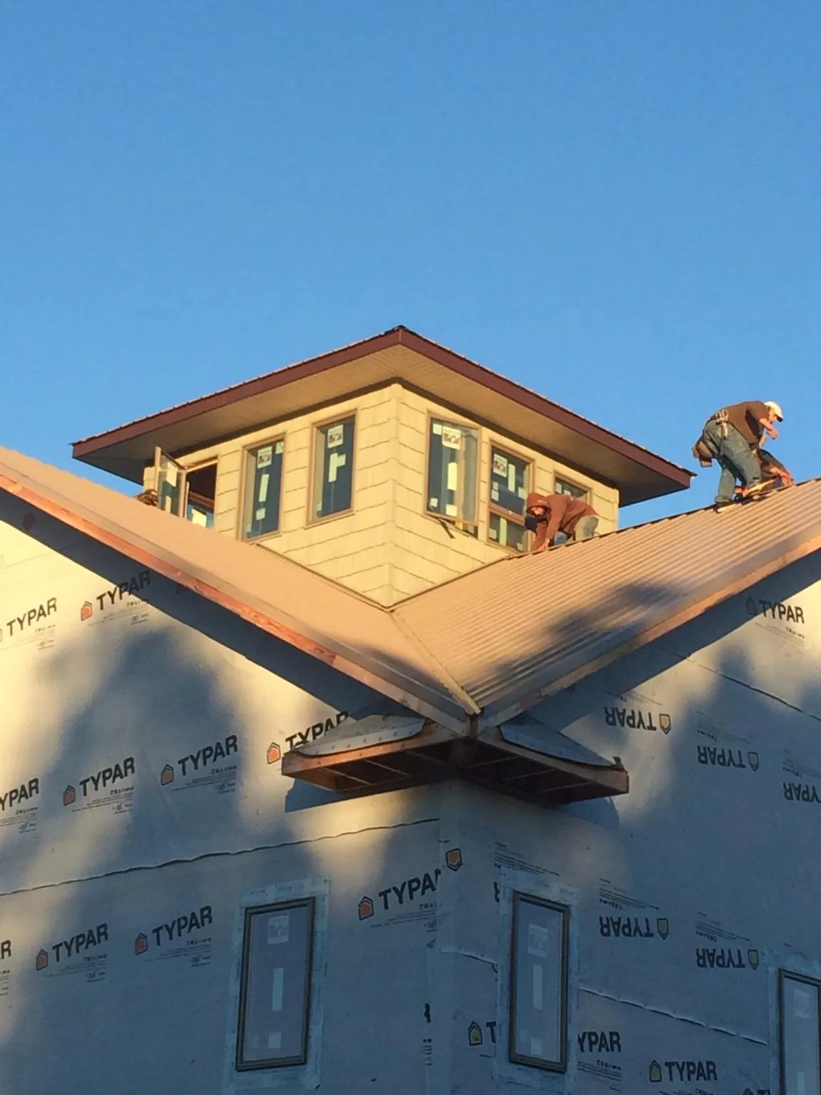Roofers working around a rooftop cupola on a new metal roof at sunset — Roof Waterproofing in Nucla by Roofing Brothers